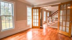 an empty living room with wood floors and open doors leading to the second floor area