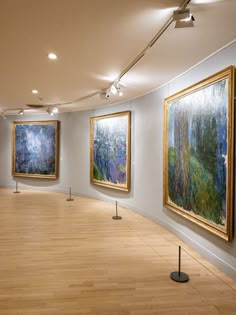 an empty room with paintings on the wall and wooden flooring in front of it