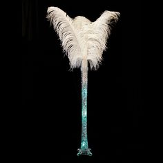 a tall glass vase with white feathers on it's sides and a black background