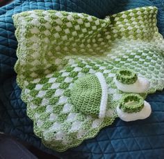 a green and white crocheted blanket on top of a blue quilted bed