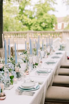 a long table is set with blue and white plates, silverware, and floral centerpieces