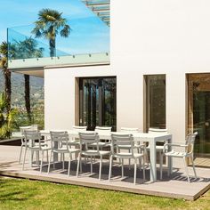 a white table and chairs sitting on top of a grass covered field next to a building