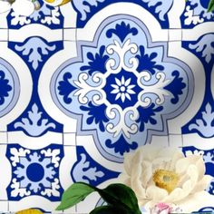 a white flower sitting on top of a blue and white tile wall