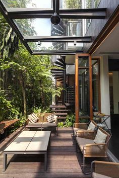 an outdoor living area with couches, tables and plants on the side walk way