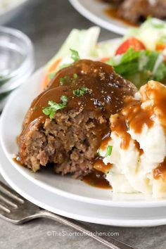 meatloaf with gravy and mashed potatoes on a plate next to salad