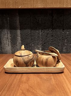 two wooden bowls and spoons on a tray