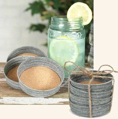 there are many round bowls with lids on the table next to a mason jar filled with limeade