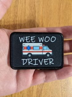 a hand holding a patch with the words wee woo driver on it and an ambulance