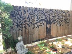 a statue sitting in the middle of a yard next to a fence with a tree on it