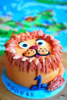 a lion cake with orange frosting and blue icing on a wooden table top