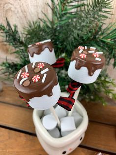 three chocolate covered marshmallows sitting in a cup on top of a table