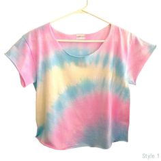 a pink, blue and yellow tie dye shirt hanging on a hanger against a white wall