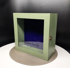 a green frame with a blue glass in it on top of a white tablecloth