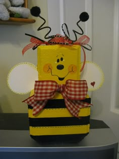 a yellow and black box with a red bow on it's head sitting on top of a table