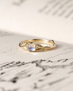 a gold ring sitting on top of an old sheet of music paper with writing in the background