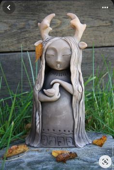 a ceramic statue of a woman with horns on her head holding a bird in her hand