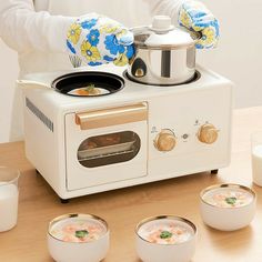 a woman is preparing food in front of an electric stove with four bowls on the table