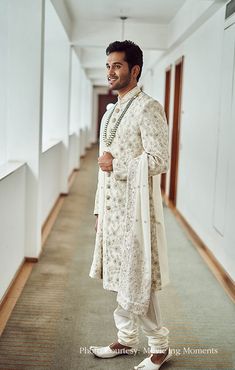 a man standing in a hallway wearing a white outfit