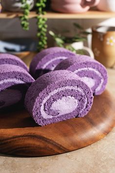 purple rolled up towels sitting on top of a wooden cutting board