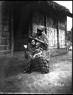 black and white photograph of four people sitting on the front steps of a house,