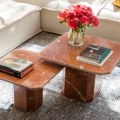 a marble coffee table with flowers in a vase and books on the end tables next to it