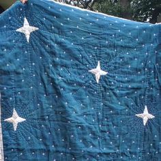 someone holding up a quilt with white stars on it