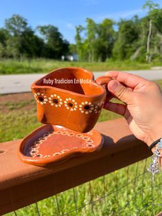 a hand holding a small cup on top of a wooden rail