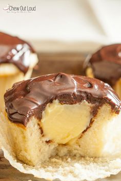 chocolate covered doughnuts sitting on top of a wooden cutting board with one bite taken out