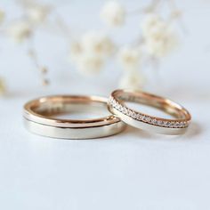 two gold wedding bands with white diamonds on the top and bottom, sitting next to each other