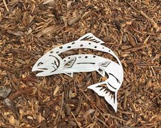 two fish cutouts are laying on some wood chips