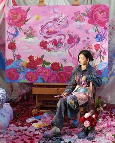 a woman sitting on a chair in front of a large painting with flowers all over it