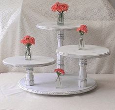 three tiered white cake stand with red flowers in vases on each one side