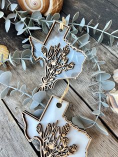 two metal ornaments sitting on top of a wooden table next to sea shells and seashells