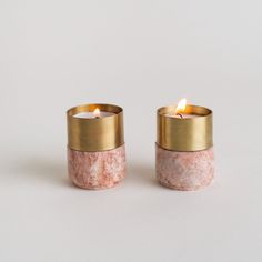 two small candles with gold rims and pink marble in front of a white background