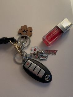 a keychain with two keys attached to it next to a bottle of cologne