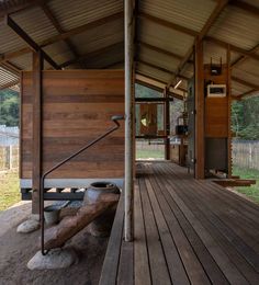 a wooden porch with a bench on the side and a grill in the back ground