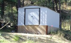 a white shed sitting in the middle of a forest