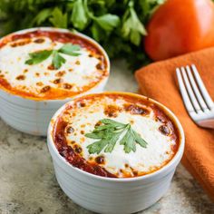 two white bowls filled with lasagna sauce and garnished with parsley