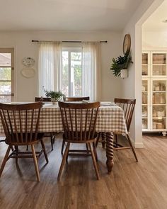 a dining room table and chairs with a checkered tablecloth on it in front of a window