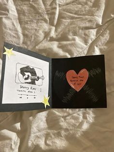 an open book with writing on it and a heart - shaped card in the middle