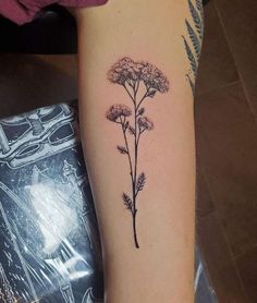 a woman's arm with a small flower tattoo on the left side of her arm