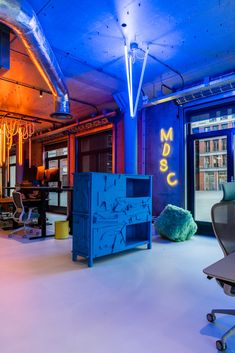 an office with neon lights and furniture in the room, including a blue cabinet that says magic