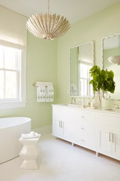 a bathroom with green walls and white fixtures, including a large mirror over the bathtub