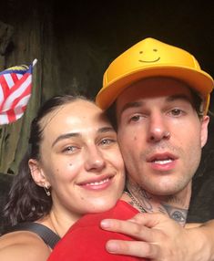 a man and woman are posing for a photo with an american flag in the background