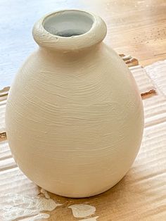 a white vase sitting on top of a wooden table