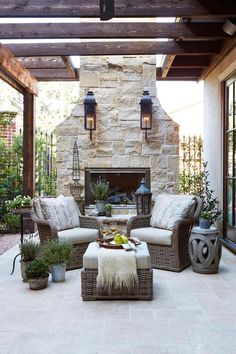 an outdoor living room with stone fireplace and furniture