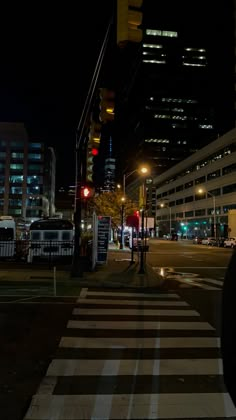 a city street at night with traffic lights on and buildings in the backround