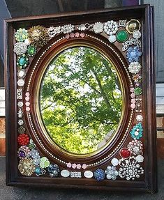 there is a mirror that has many different things in the frame and it appears to be made out of buttons