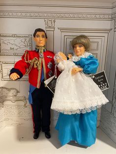 two dolls dressed in formal clothing standing next to each other