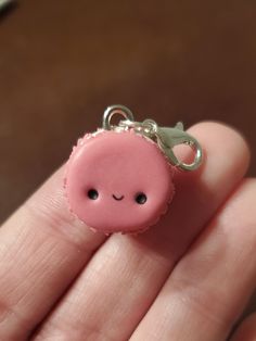 a small pink pig keychain sitting on top of a person's finger